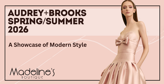 A model wearing a strapless Audrey+Brooks Spring/Summer 2026 gown featuring a structured statement collar in an exaggerated fan shape, paired with minimal makeup and a sleek bun.