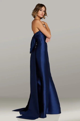 Model wearing Gia Franco 12411 strapless fit-and-flare gown featuring a dramatic back bow detail and floor-length train, ideal for formal evening or mother of the bride events.