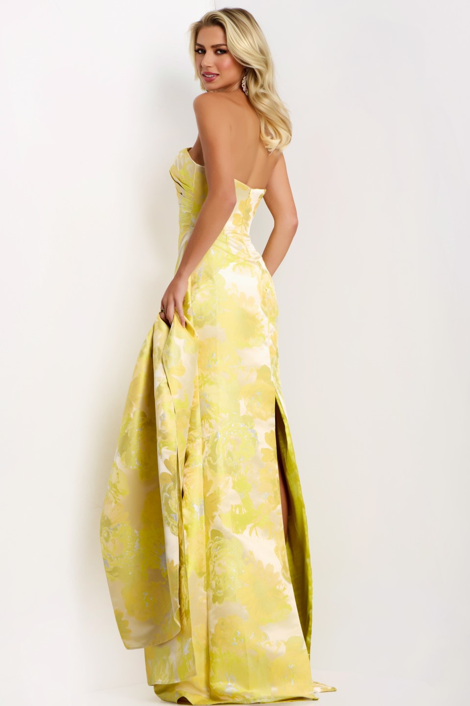 Model wearing Jovani 45289 strapless floral column gown with straight neckline, high slit, and matching drape.