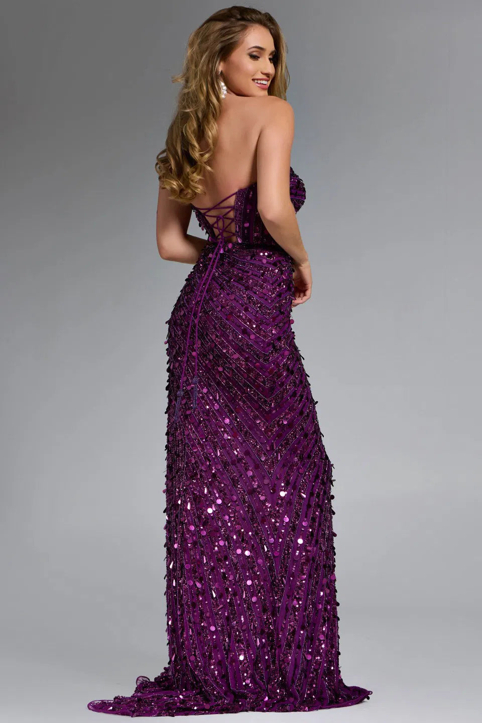Model wearing Jovani 46714 strapless beaded gown with high slit and lace-up back in gold, blue, and lilac.
