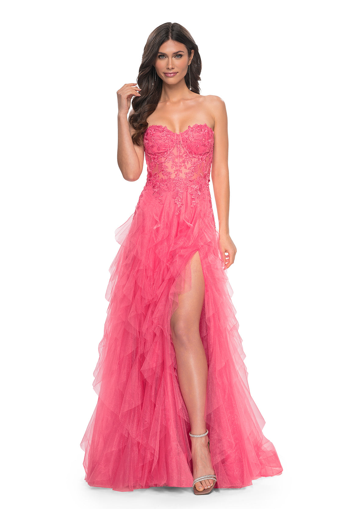 La Femme 32286 Illusion Lace Bustier A-Line Prom Gown - A captivating A-line gown featuring a ruffle tulle skirt, high slit, and illusion lace bustier bodice for a glamorous and sophisticated prom look. The model is wearing the dress in the color coral.