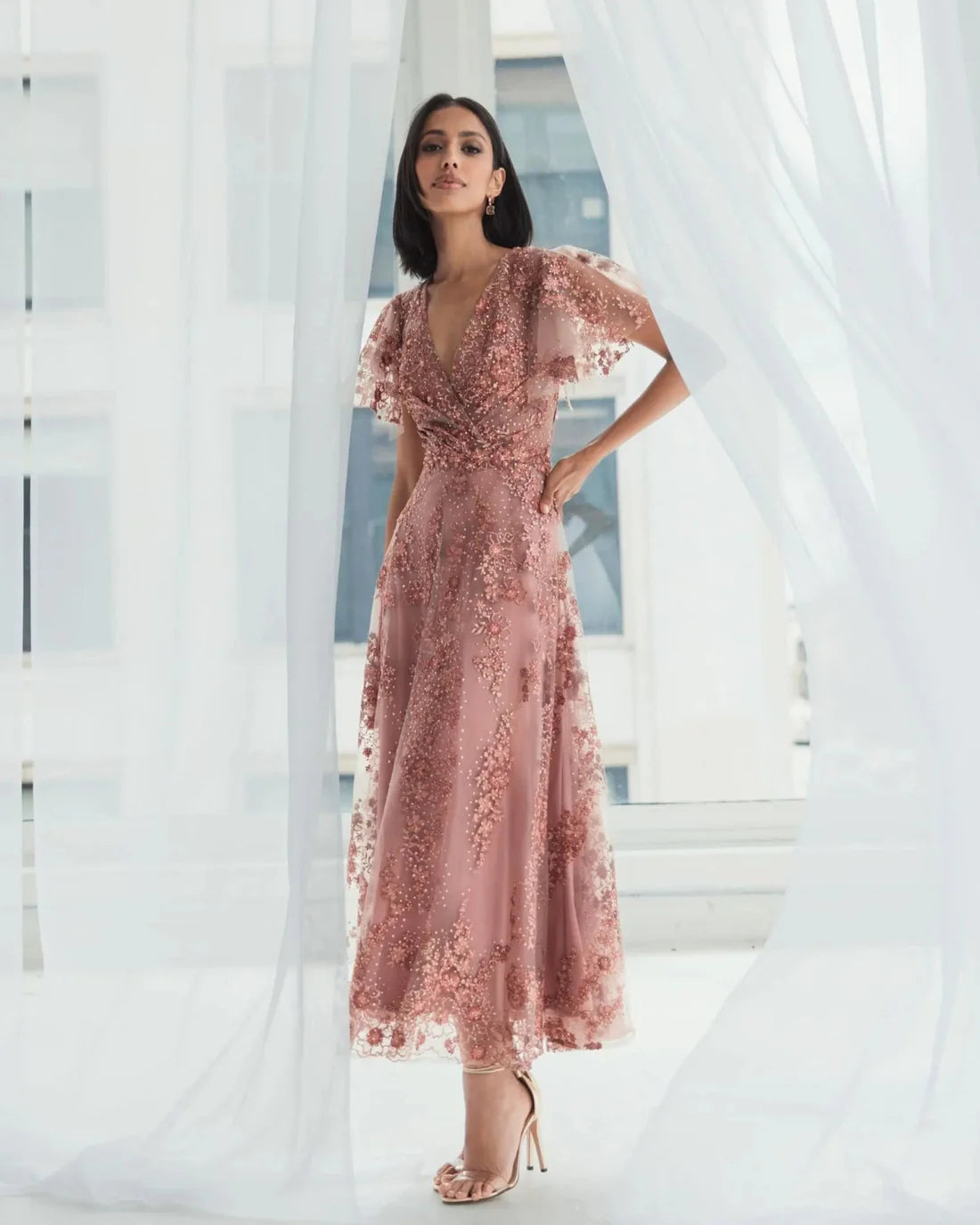 Model wearing Mac Duggal 20486 gown with faux wrap v-neckline, flutter sleeves, and rhinestone floral embellishments.