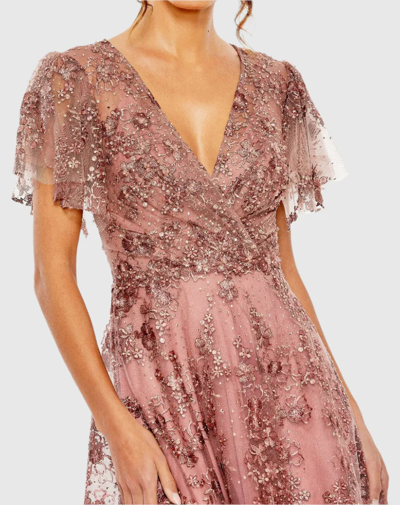 Model wearing Mac Duggal 20486 gown with faux wrap v-neckline, flutter sleeves, and rhinestone floral embellishments.