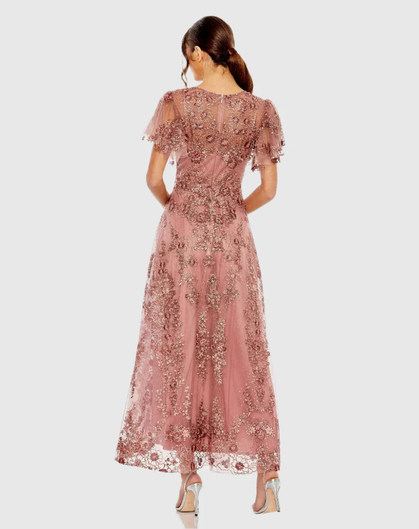 Model wearing Mac Duggal 20486 gown with faux wrap v-neckline, flutter sleeves, and rhinestone floral embellishments.
