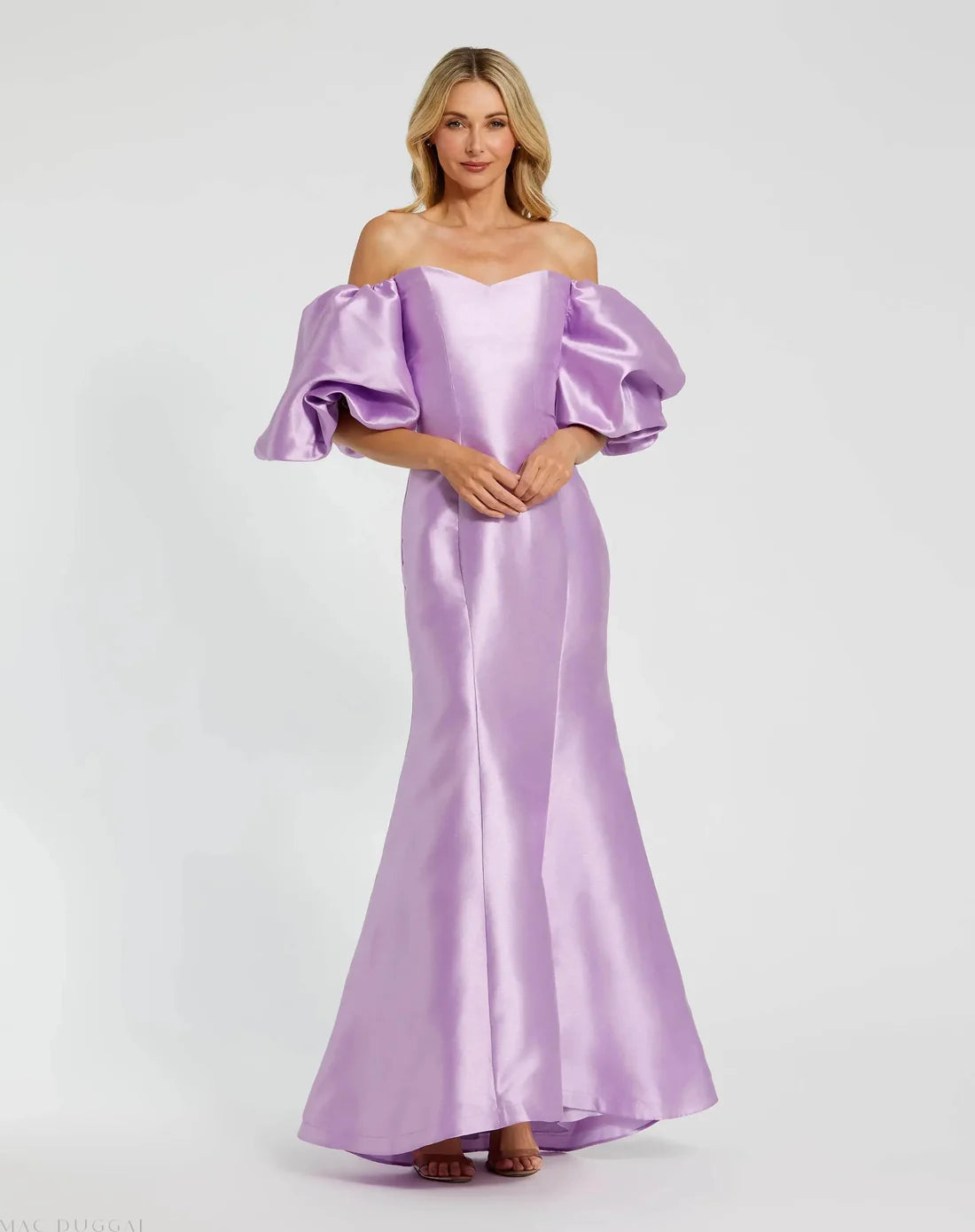 Model wearing Mac Duggal 50677 off-the-shoulder satin gown with puff sleeves, mermaid silhouette, and sweeping train. Model is wearing the color lilac. Front view.