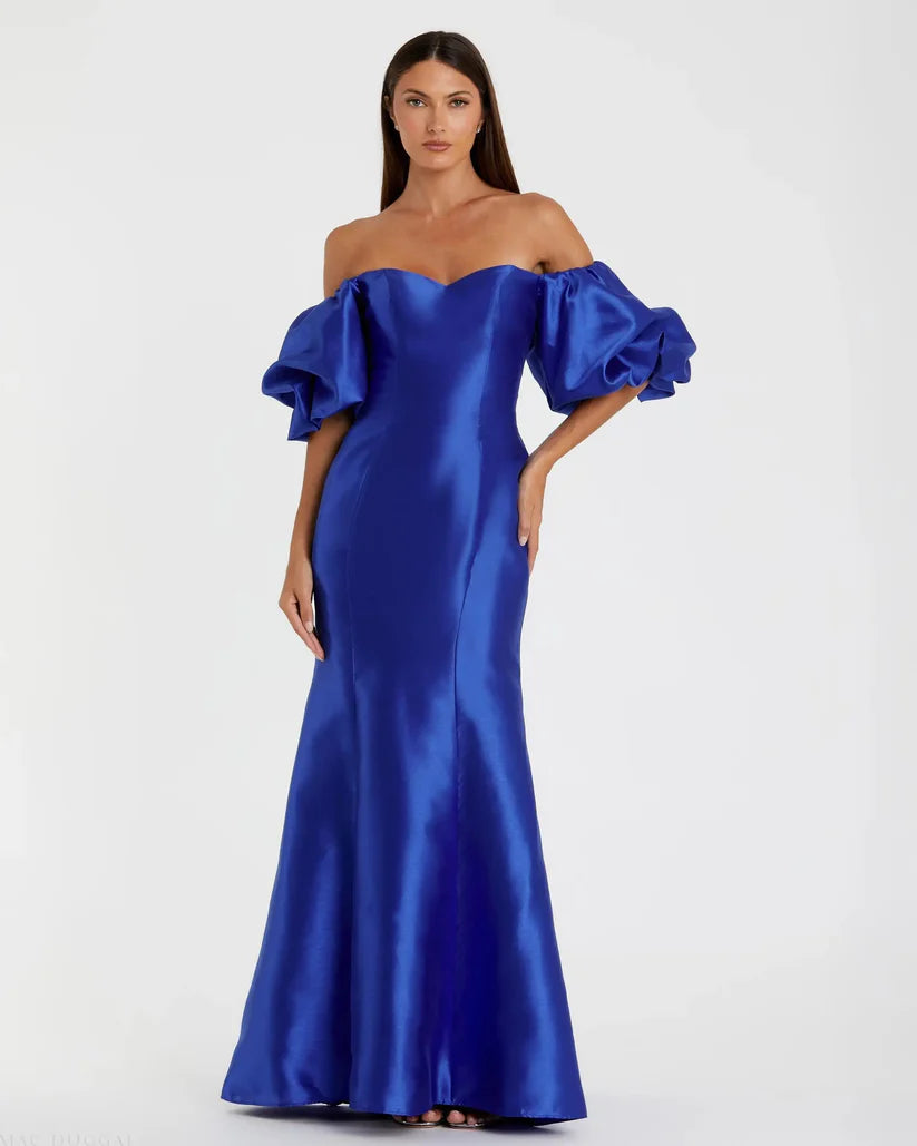Model wearing Mac Duggal 50677 off-the-shoulder satin gown with puff sleeves, mermaid silhouette, and sweeping train. Model is wearing the color royal blue. Front view.