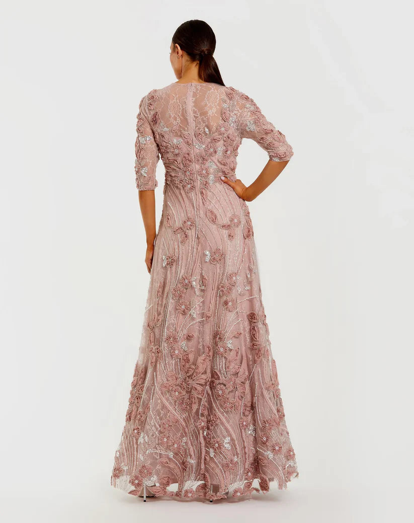 Model wearing Mac Duggal 69016 gown with illusion neckline, 3/4 sheer sleeves, 3D rosettes, and a flowing embellished skirt. Back View.