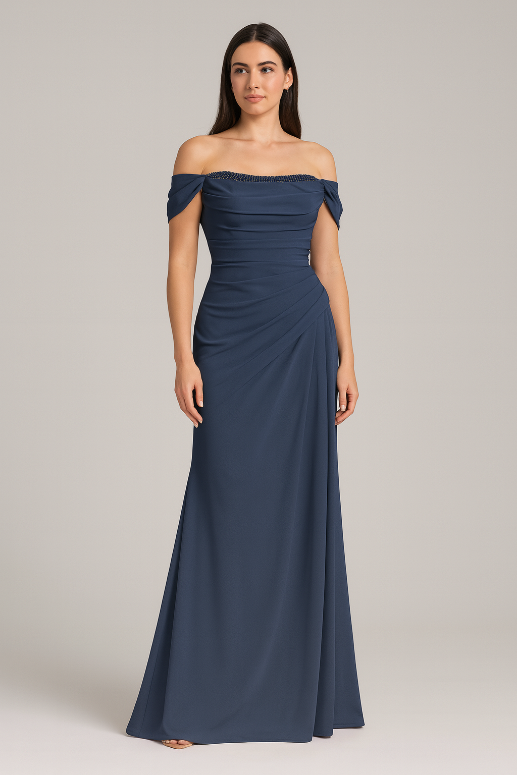 Model wearing Madeline’s Catherine off-shoulder beaded gown with ruched bodice and floor-length skirt. Model is wearing the dress in the color navy. Front view.