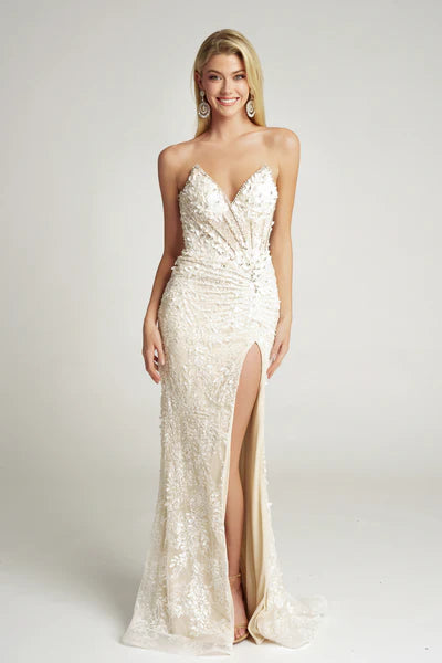 Woman wearing a strapless, embellished evening gown with a high slit on a plain background