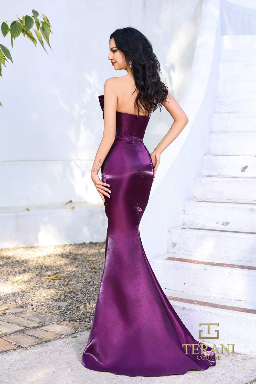 Model wearing Terani 252E5513 one-shoulder shimmer organza evening gown with peplum waist accent and fitted flared silhouette. Color Plum. Back View.