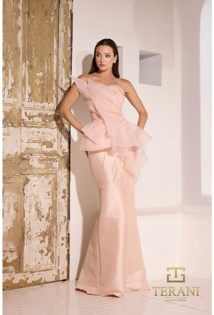 Model wearing Terani Couture 252E5550 strapless gown with peplum detail and mermaid silhouette on the beach. Model is wearing the dress in the color blush.