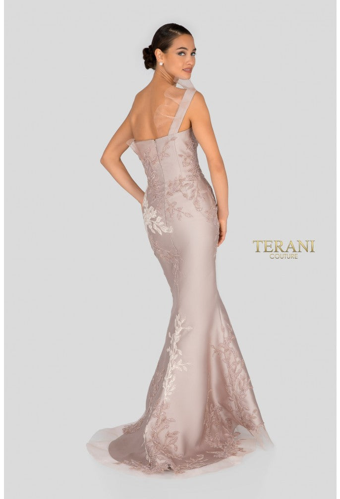 Woman wearing a elegant one-shoulder dress with floral lace details on a light gray background, featuring the Terani brand.
