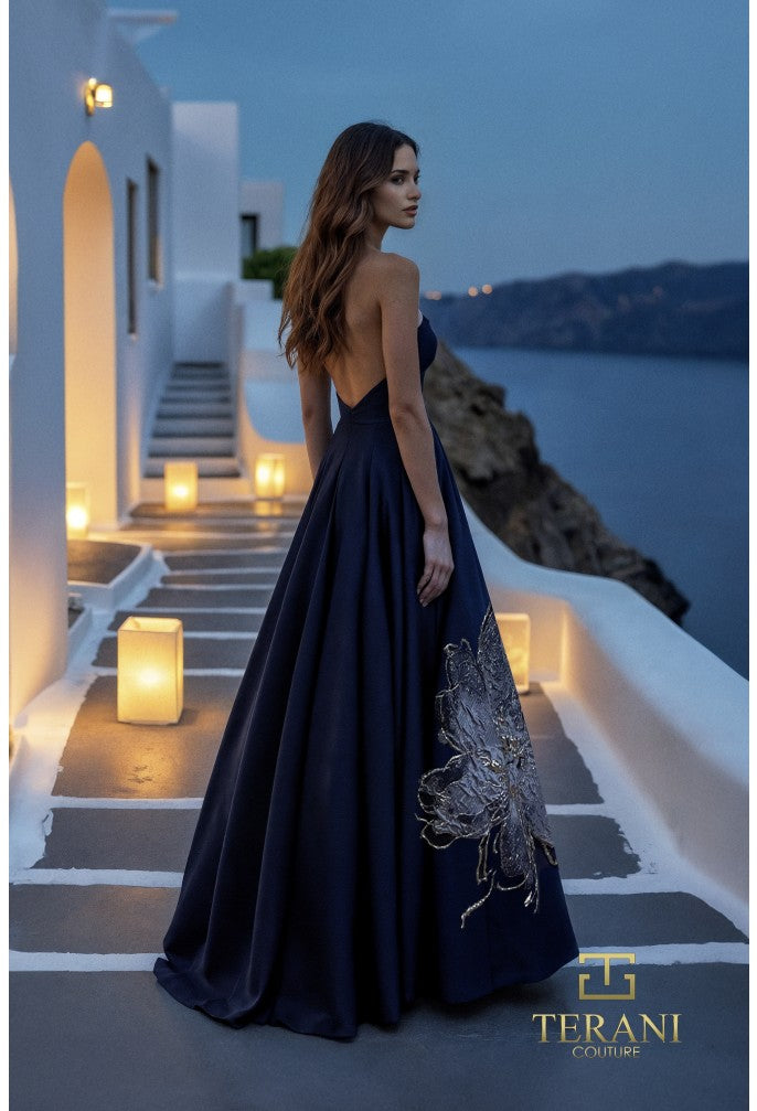 Model wearing Terani Couture 261E6544 strapless evening gown featuring a structured bodice, floral appliqué detailing, and a flowing floor-length skirt.