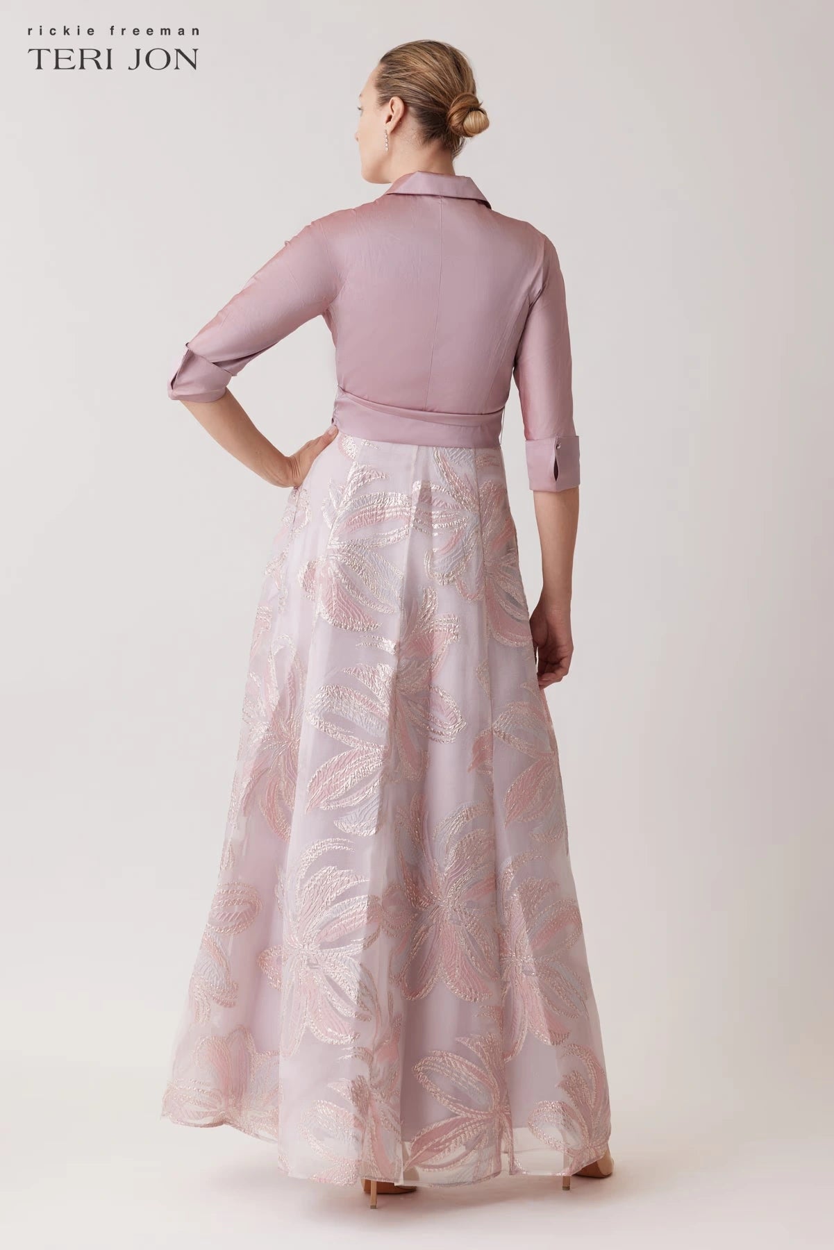 Model wearing Teri Jon 259079 gown featuring a collared neckline, button-up closure, removable sash, and a metallic organza embroidered skirt.