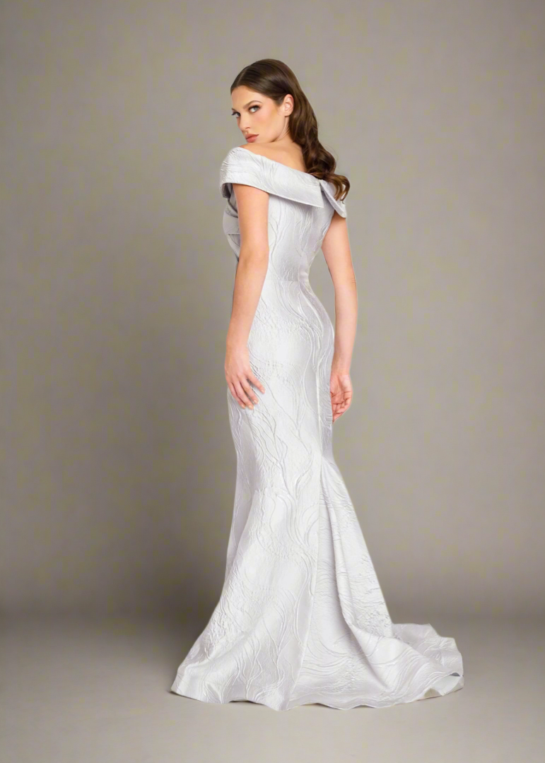 Nicole Bakti 7299 Off-Shoulder Metallic Jacquard Gown – Elegant off-shoulder gown with fitted silhouette and flared hem in luxurious metallic jacquard fabric.