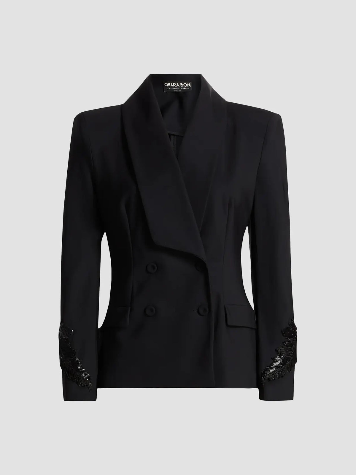 A black double-breasted blazer with a shawl collar and decorative black lace detailing on the cuffs, shown on a neutral light gray background. 