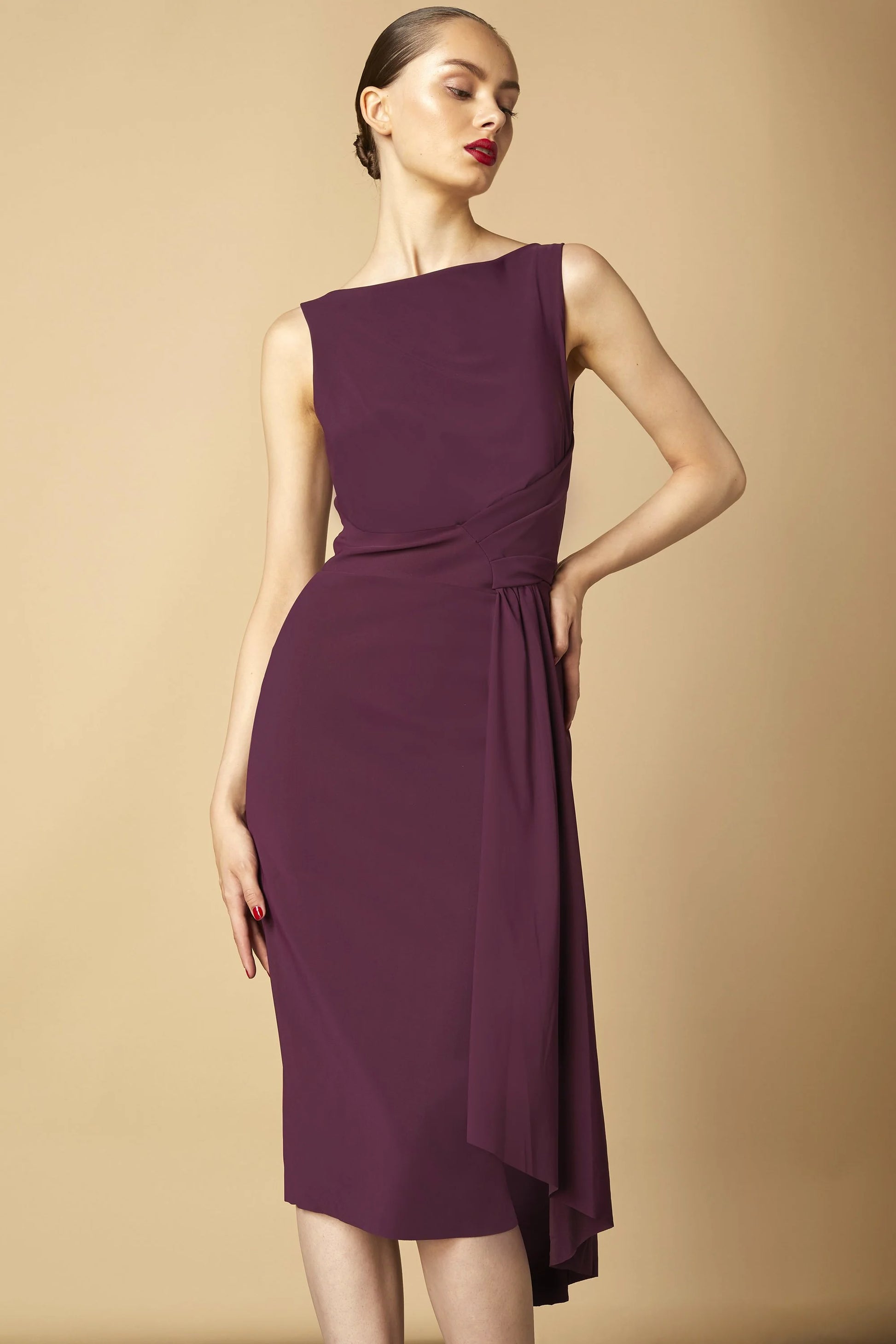 Model wearing Chiara Boni Cinthia draped asymmetric midi dress with bateau neckline and gathered waist detail.