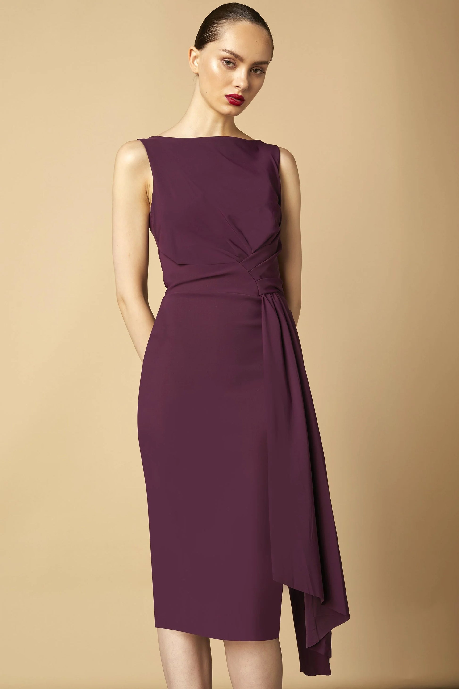 Model wearing Chiara Boni Cinthia draped asymmetric midi dress with bateau neckline and gathered waist detail.