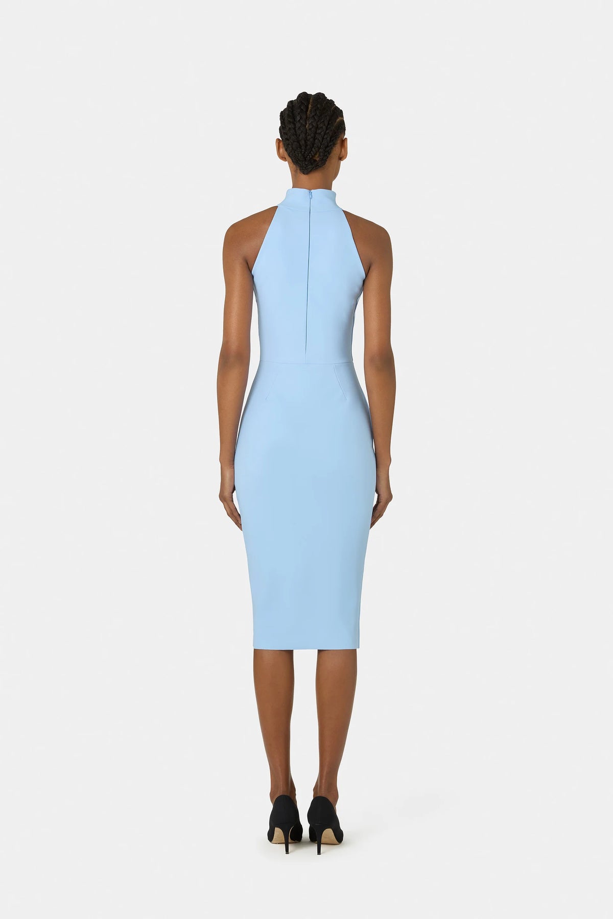 A model shown from the back wearing a light blue sleeveless halter-neck midi dress, paired with black high heels, against a solid light gray background.