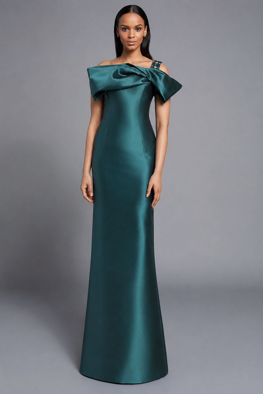 A woman modeling a floor-length off-the-shoulder gown in teal satin against a neutral gray studio background.