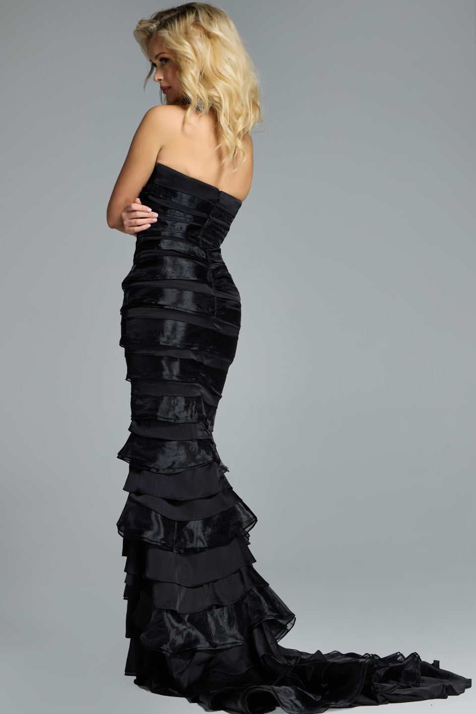 Model wearing Jovani 44383 strapless tiered ruffle gown with fitted silhouette and sweep train.