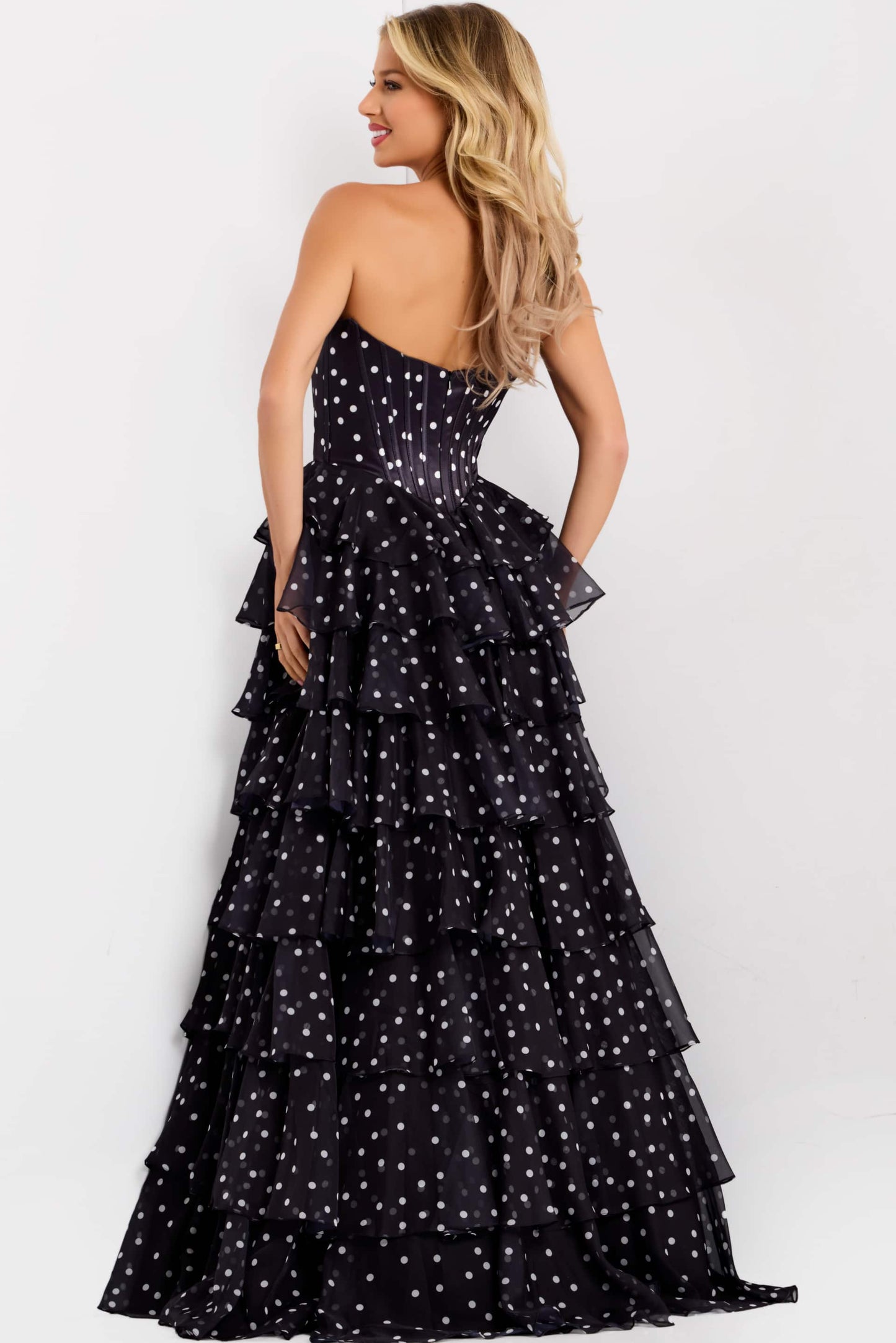 Woman wearing a black polka dot evening gown against a white background
