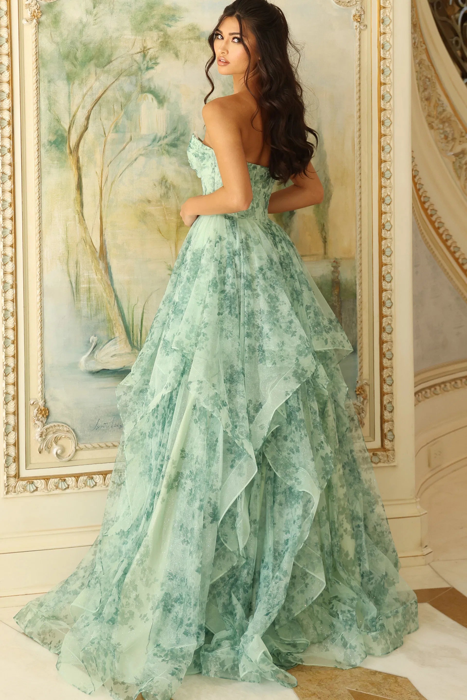 Woman in a green floral gown standing in an ornate room.