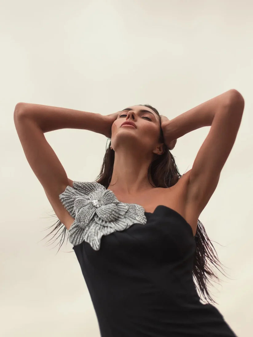 Model wearing Mac Duggal 11810 one-shoulder trumpet gown with flower detail, posing outdoors.
