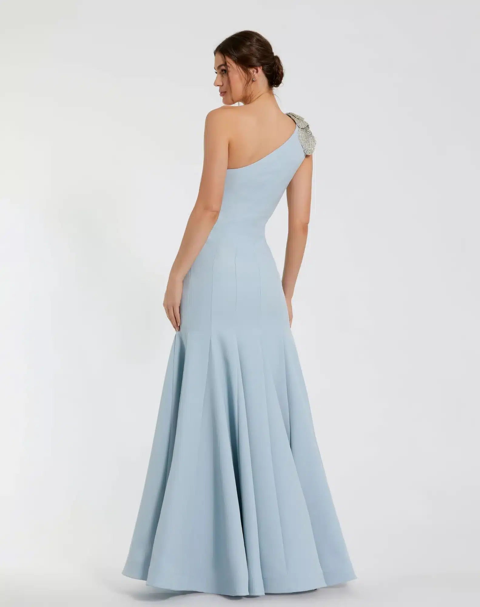 Model wearing Mac Duggal 11810 one-shoulder trumpet gown with flower detail.  Model wearing the dress in the color powder blue.  Back view.