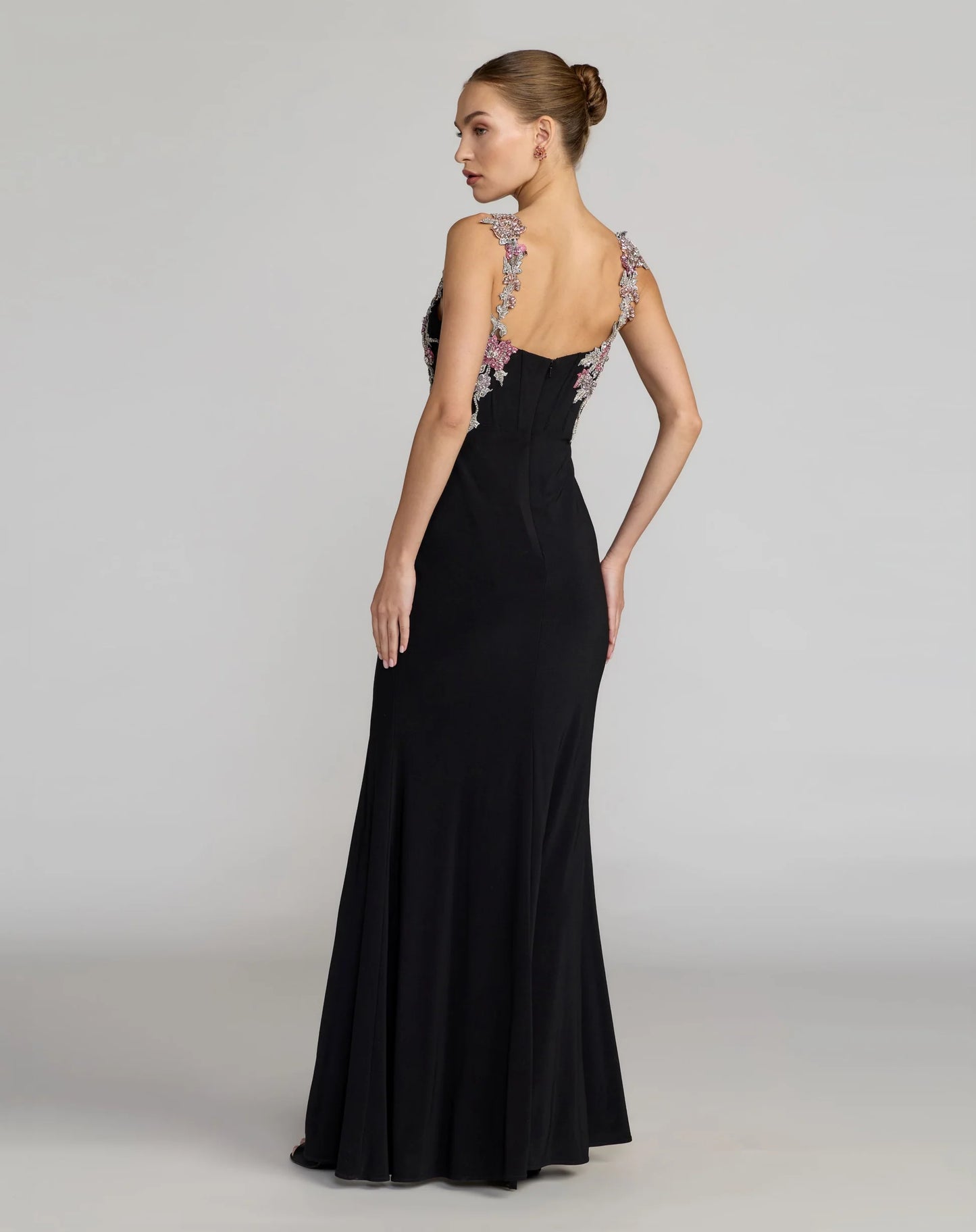 Black evening gown with floral embellishments on a plain background