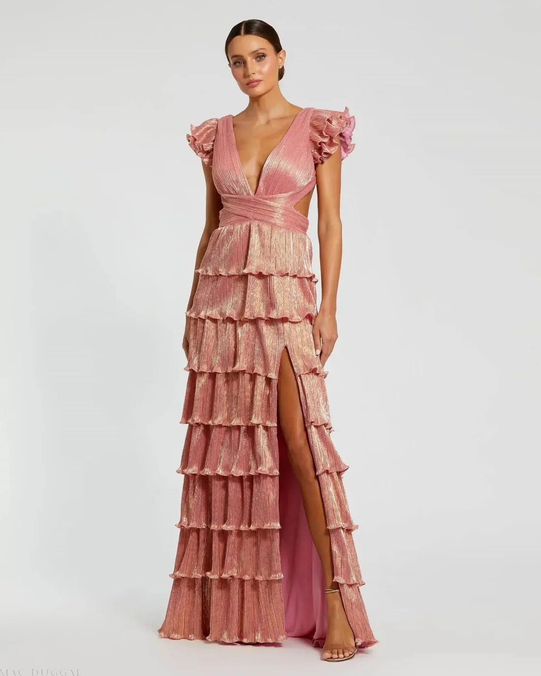 Model wearing Mac Duggal 26740 gown with deep V-neckline, ruffled sleeves, tiered pleated skirt, lace-up back, and thigh-high slit.  Model is wearing the color coral.