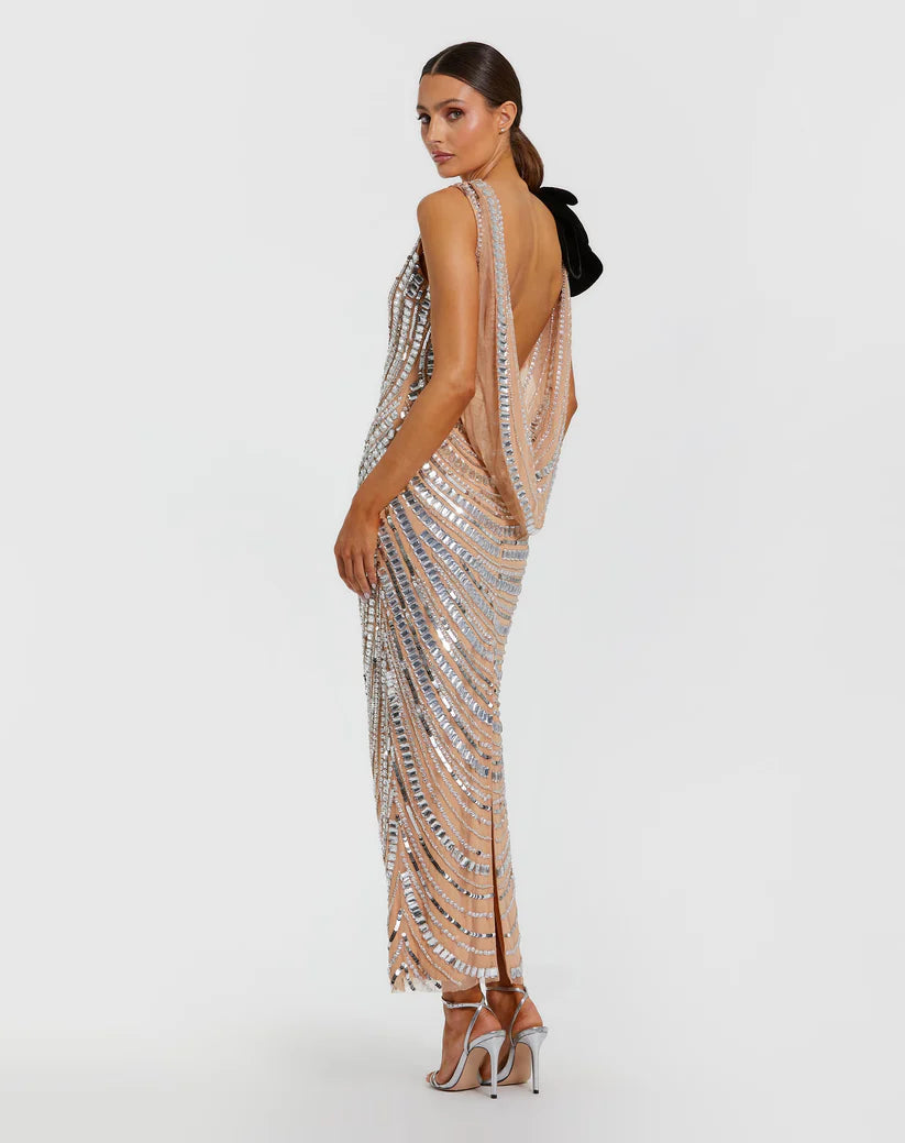 Model wearing Mac Duggal 94285 beaded gown with one-shoulder flower accent, cowl draped back, and ankle-length hem.