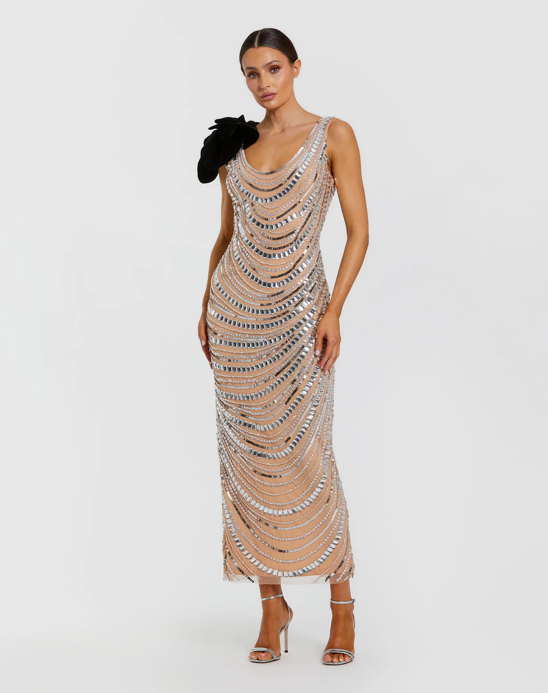 Model wearing Mac Duggal 94285 beaded gown with one-shoulder flower accent, cowl draped back, and ankle-length hem.