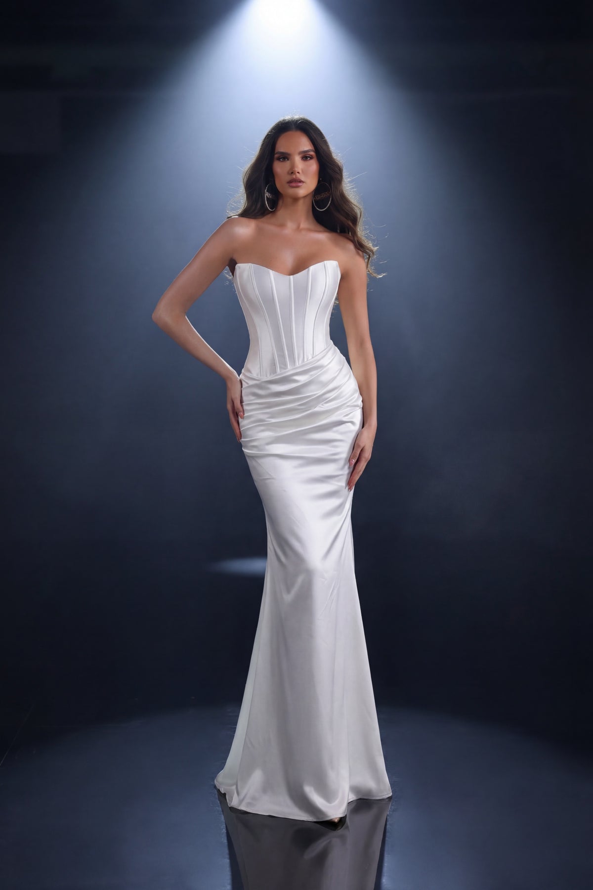 Woman wearing a white strapless gown against a dark background