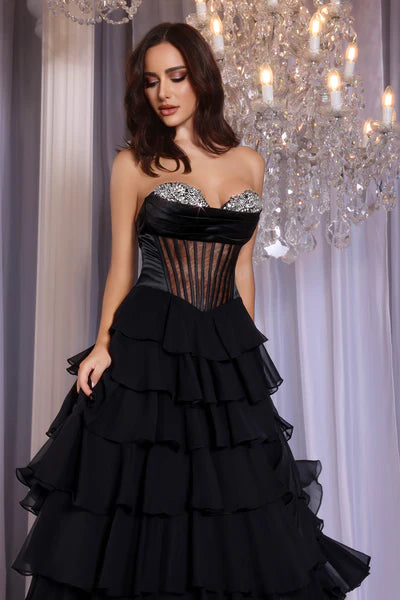 Model wearing Portia & Scarlett PS25961 gown featuring a strapless embellished bodice, sheer corset, high slit, and tiered ruffle skirt.