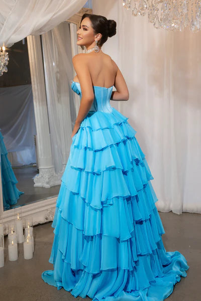 Model wearing Portia & Scarlett PS25961 gown featuring a strapless embellished bodice, sheer corset, high slit, and tiered ruffle skirt.