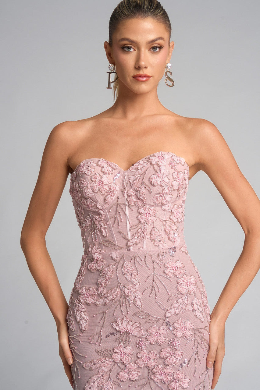 Woman wearing a strapless pink lace evening gown on a gray background