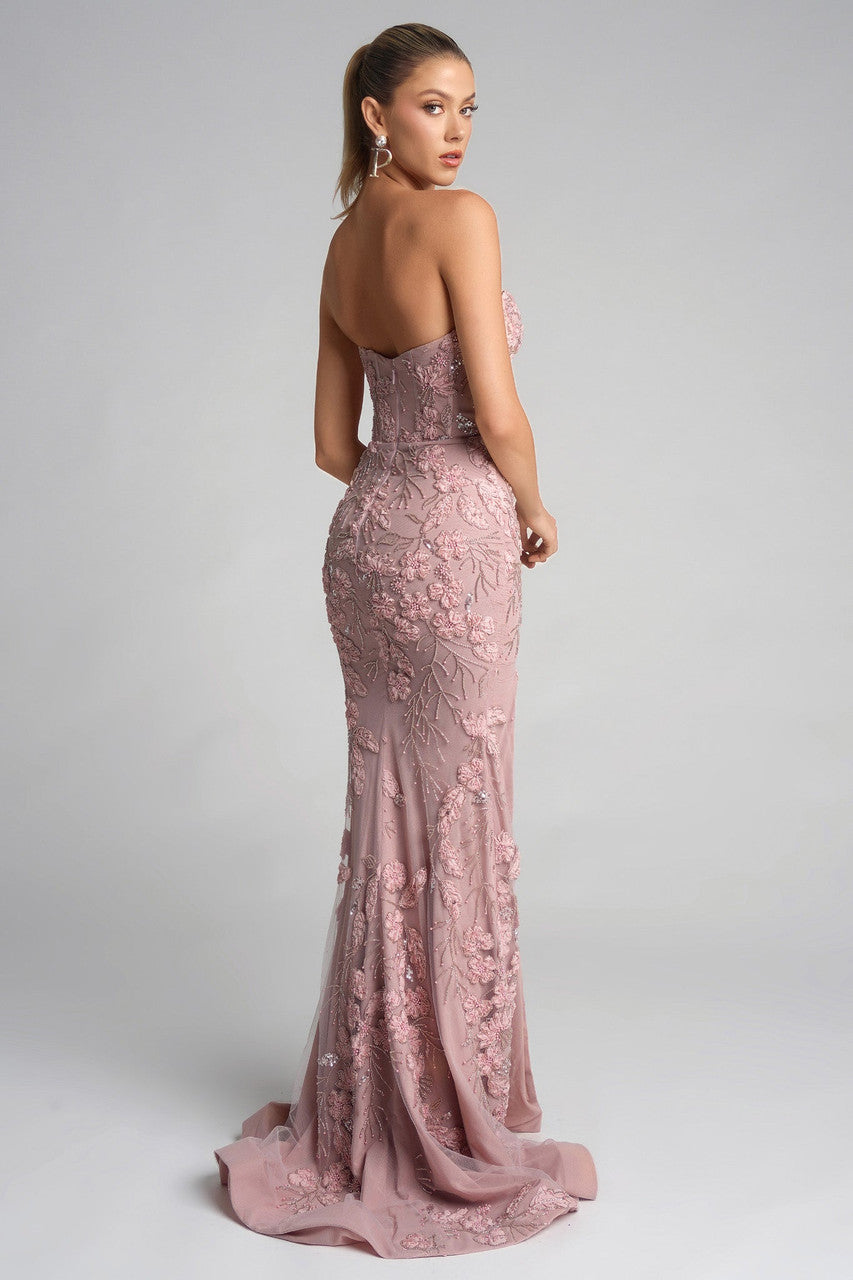 Woman wearing a pink lace evening gown on a gray background