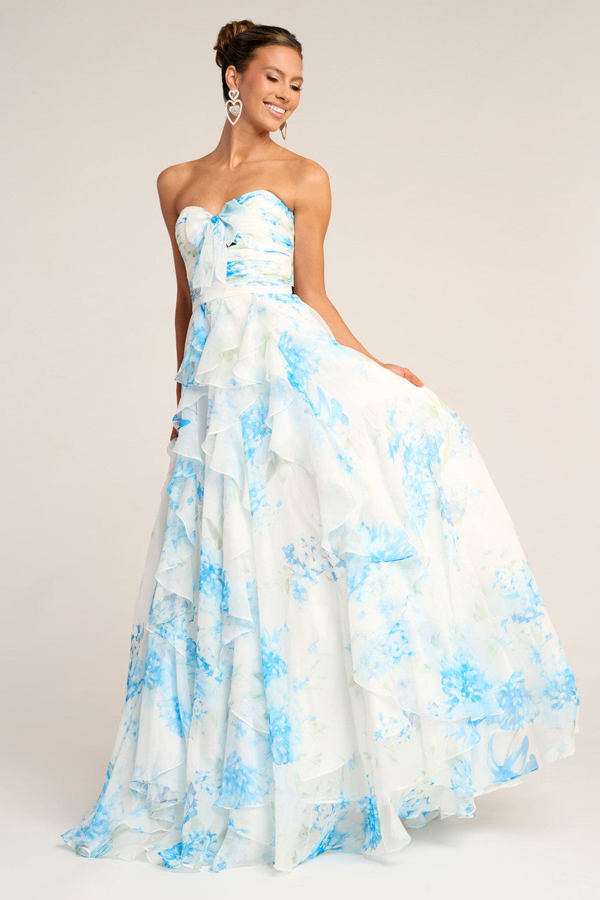 Woman wearing a strapless floral gown with blue and white flowers on a plain background