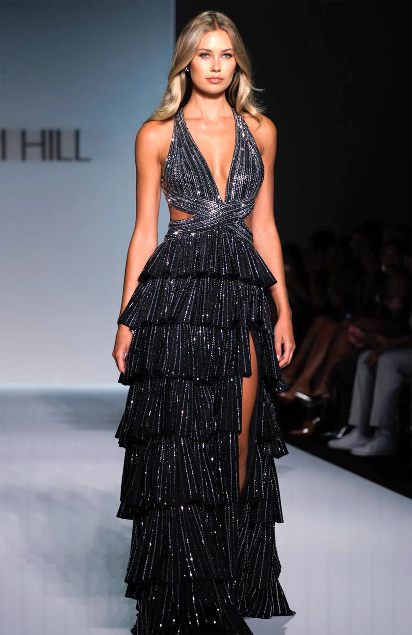 Model wearing a black, tiered dress with a plunging neckline on a runway.