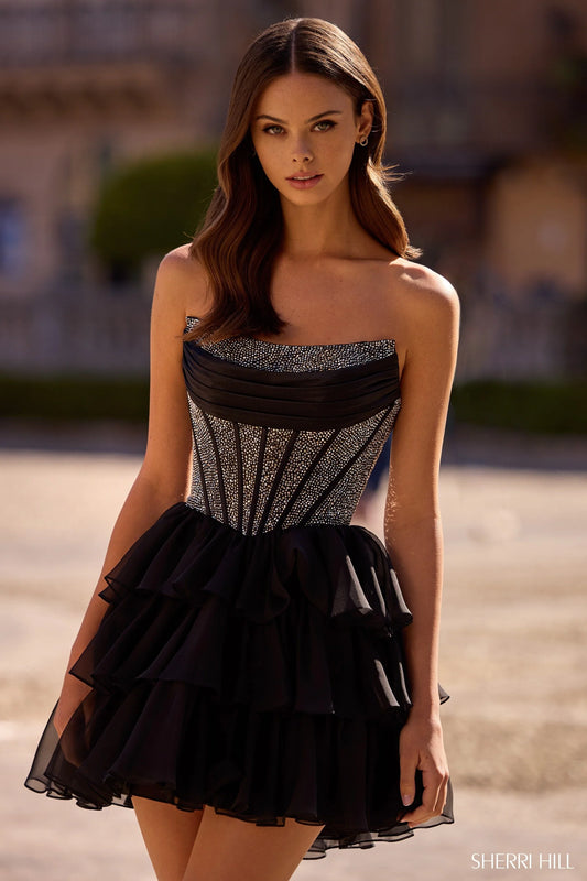 Model wearing Sherri Hill 57404 strapless cocktail dress with hot fix corset bodice and layered chiffon ruffle skirt.