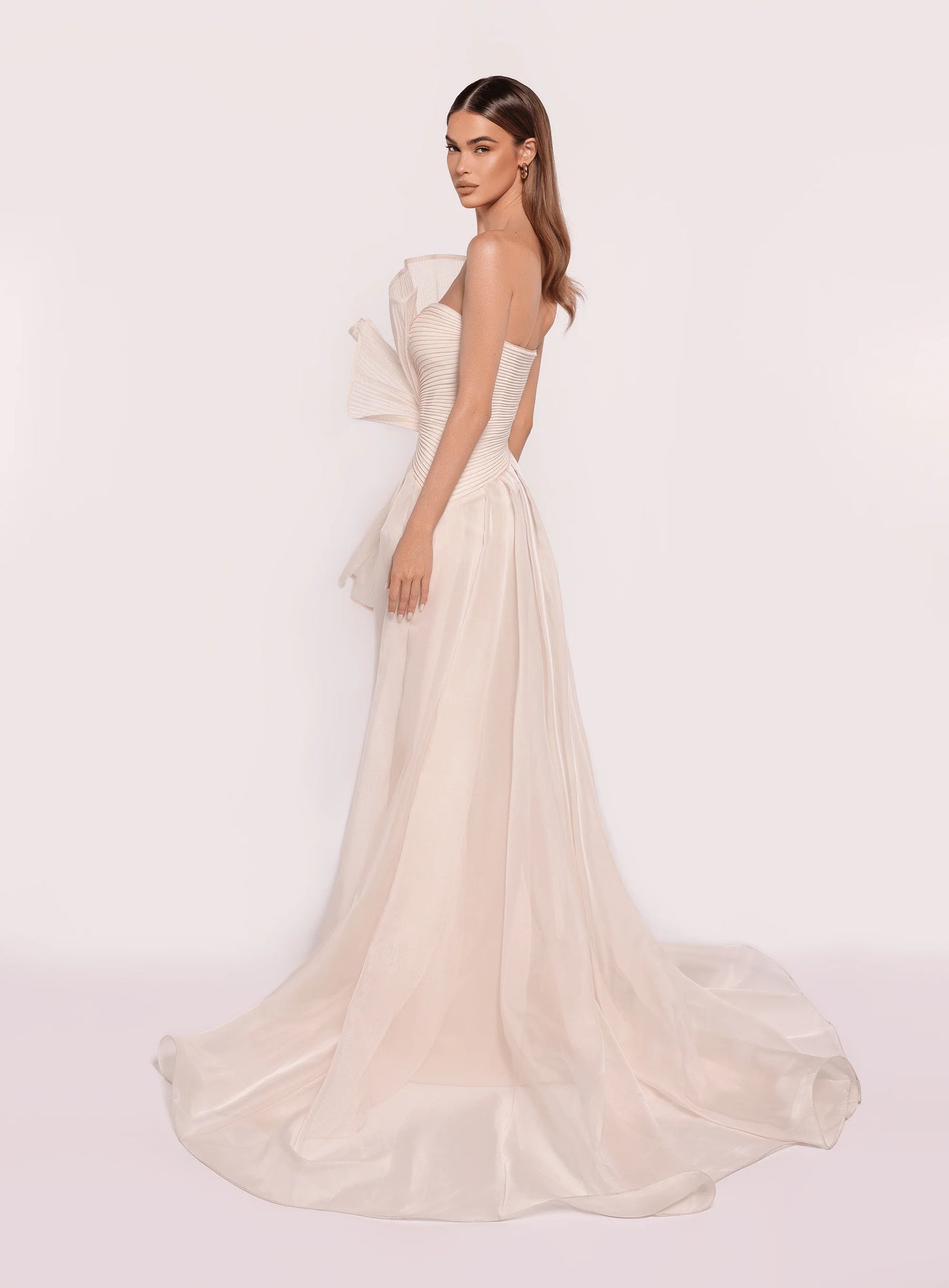 Model wearing Tarik Ediz 98708 Ronesme strapless gown in the color vanilla with sculptural pleated bodice and full A-line skirt with train, ideal for red carpet or formal events.