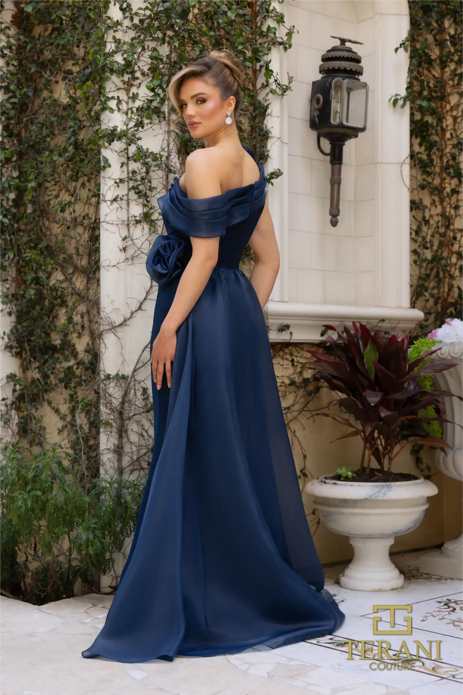 Terani Couture 242M3342 Asymmetric Off-Shoulder Gown with rose detailing, available in navy and emerald. Perfect for formal evening events and Mother of the Bride or Groom.