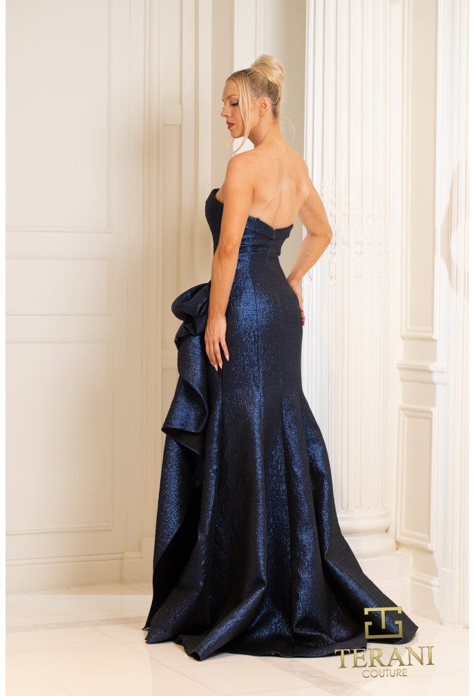 Model wearing Terani 252E5200 strapless metallic jacquard fit and flare gown with side draping detail.  Wearing Navy.  Back View.