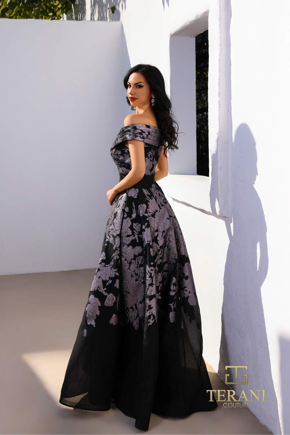 Model wearing Terani Couture 252E5188 off-shoulder A-line evening gown with floral detailing and elegant silhouette. Back View.