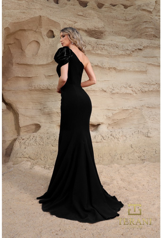 Model wearing Terani Couture 252E5514 one-shoulder gown with puff sleeve, draped bodice, and chapel train in the color black.  Back View.