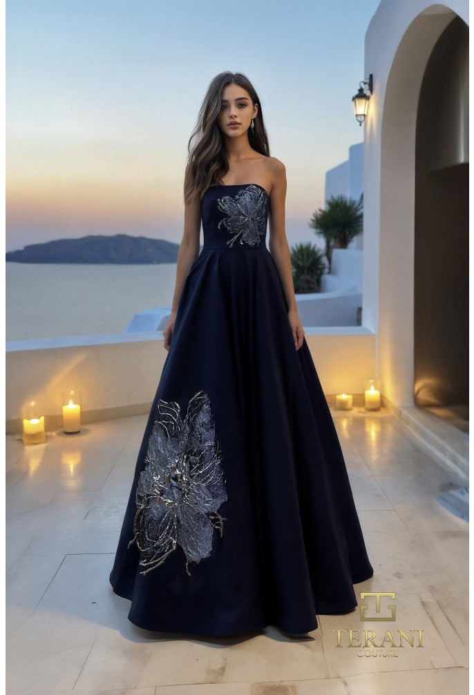 Model wearing Terani Couture 261E6544 strapless evening gown featuring a structured bodice, floral appliqué detailing, and a flowing floor-length skirt.