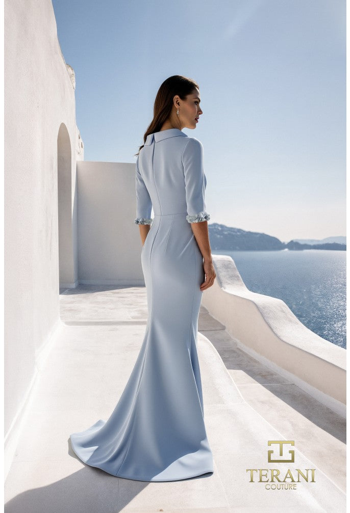 Woman in a light blue dress standing on a balcony with a scenic view of the ocean.